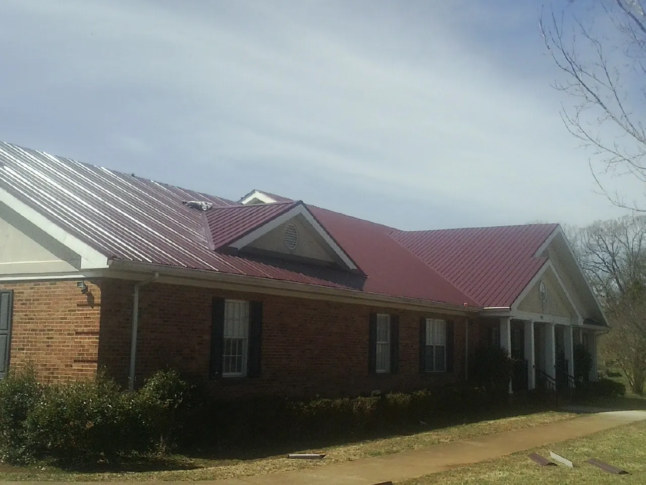 Red metal roof with gabled entries on a long brick building in Hilo