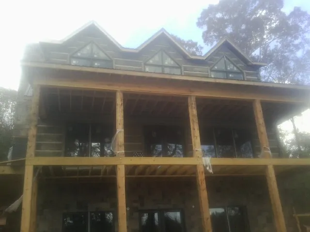 Dormers and porch framing on a large log home under construction — Roof Coating work by our crew in Hilo