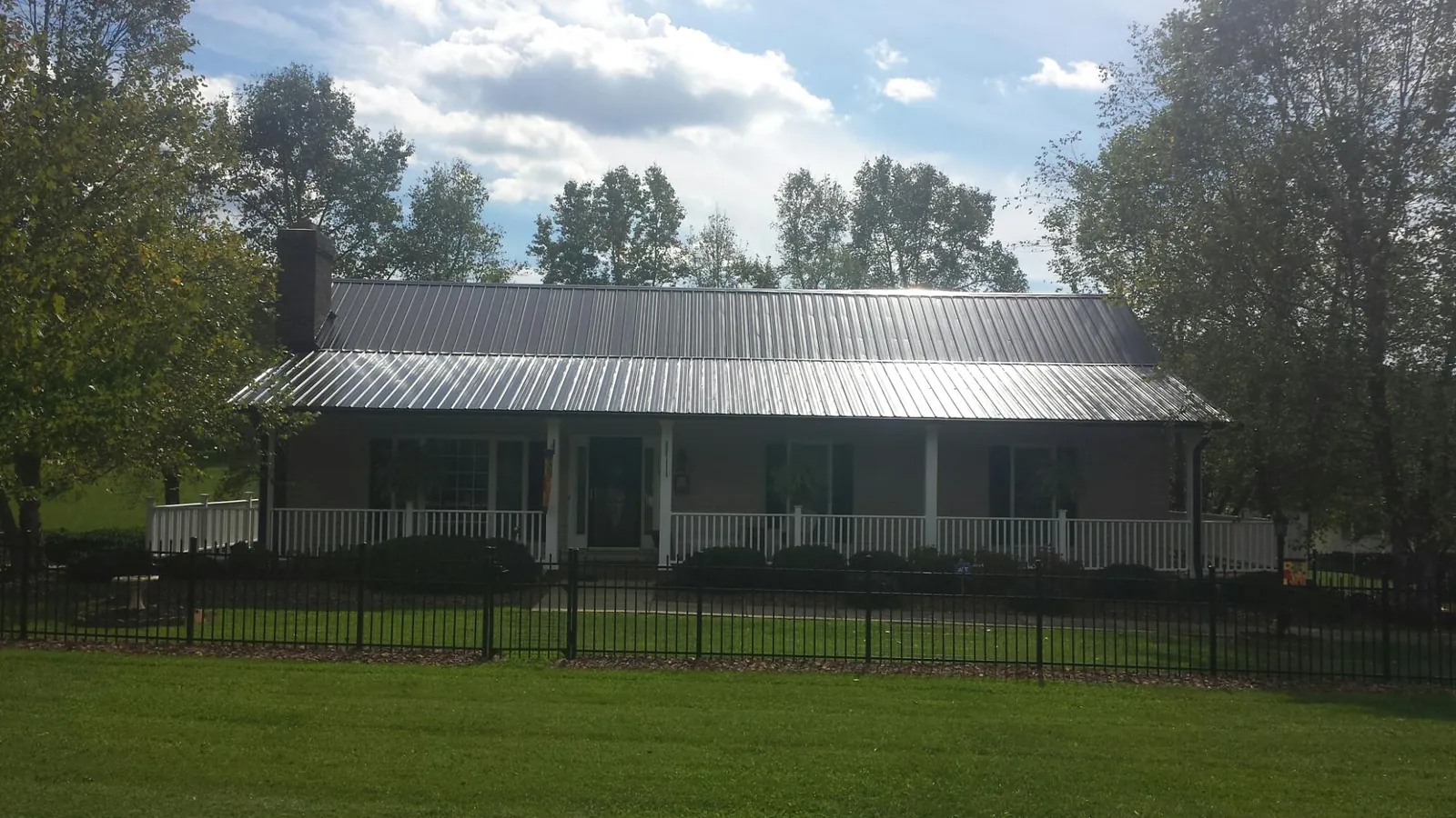 Gray metal roof on a brick ranch with a full width front porch — Gutter Guard Installation work by our crew in Hilo