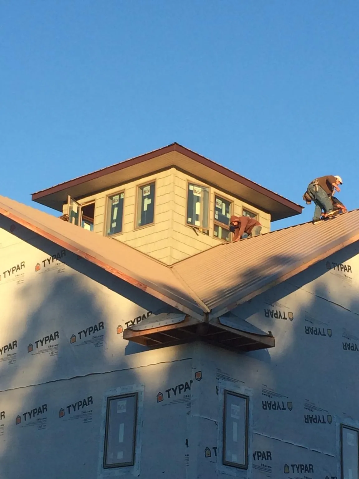 Roofers working around a rooftop cupola on a new metal roof at sunset — Roof Waterproofing in Hilo by Roofing Brothers